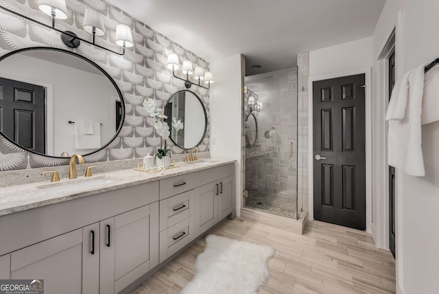 bathroom with a shower with shower door, hardwood / wood-style floors, and vanity