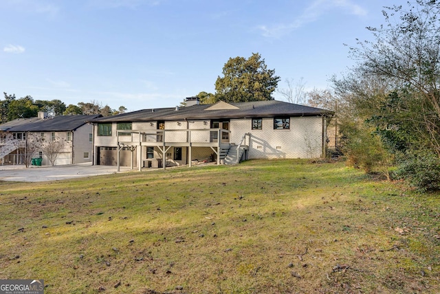 back of property featuring a garage, a wooden deck, and a lawn