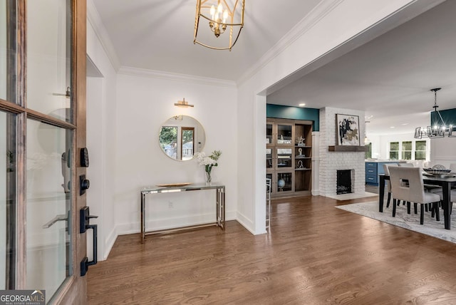 foyer entrance with a chandelier, crown molding, a fireplace, and dark hardwood / wood-style floors