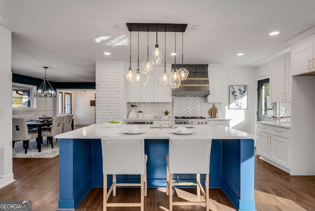 kitchen with light stone counters, a spacious island, white cabinets, and tasteful backsplash