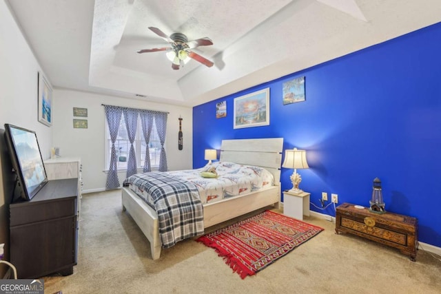 bedroom with a textured ceiling, carpet floors, a raised ceiling, and ceiling fan