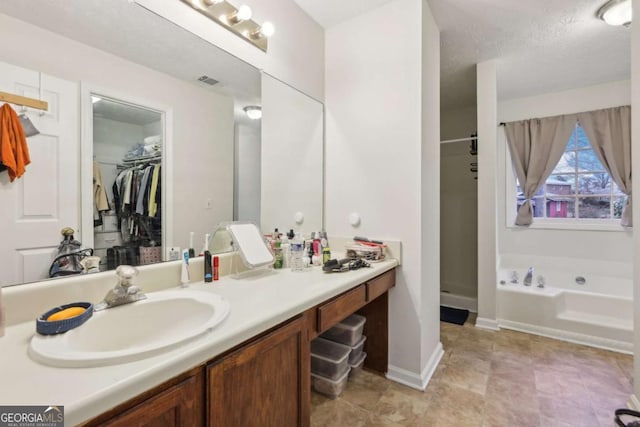 bathroom with a bathtub, a textured ceiling, and vanity