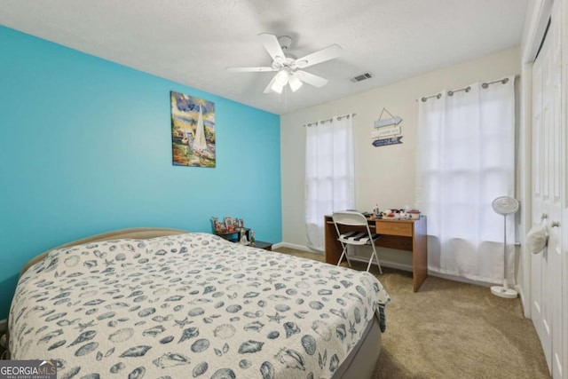 bedroom featuring ceiling fan, a closet, light carpet, and a textured ceiling