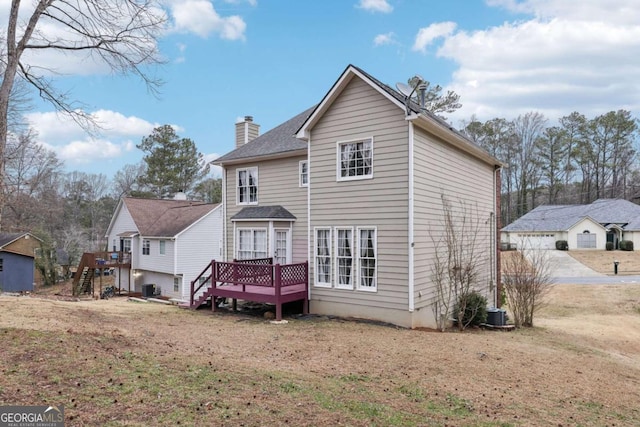 rear view of property featuring central air condition unit, a wooden deck, and a lawn