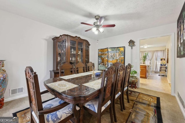 carpeted dining space with ceiling fan and a textured ceiling