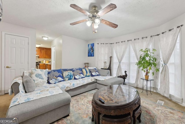 living room with ceiling fan, light colored carpet, and a textured ceiling