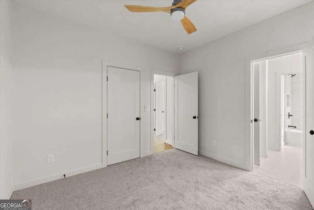 unfurnished bedroom featuring light colored carpet, ensuite bath, and ceiling fan