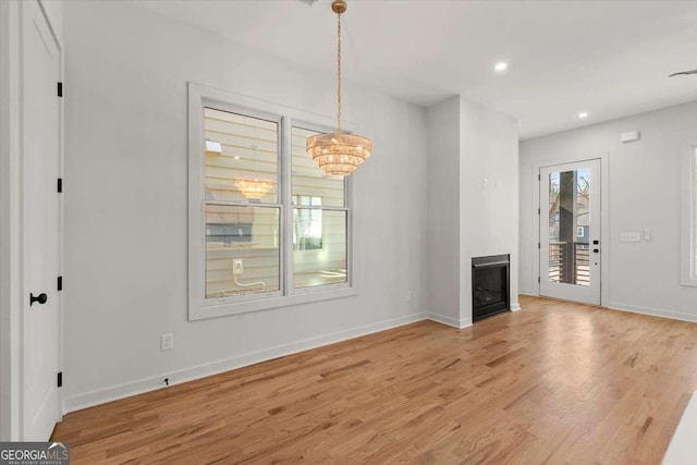 unfurnished living room with light hardwood / wood-style floors and an inviting chandelier