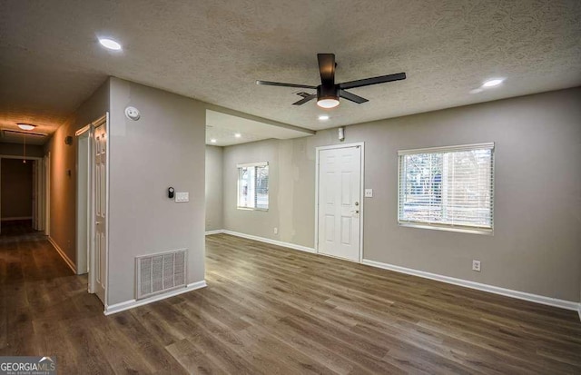 interior space with a wealth of natural light, ceiling fan, dark hardwood / wood-style floors, and a textured ceiling