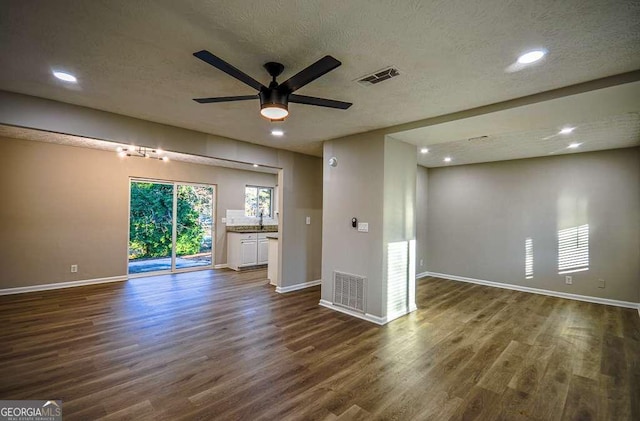 unfurnished living room with ceiling fan, dark hardwood / wood-style floors, and a textured ceiling