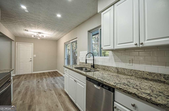 kitchen featuring light stone countertops, white cabinetry, sink, stainless steel dishwasher, and a textured ceiling