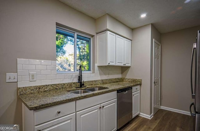 kitchen featuring white cabinets, appliances with stainless steel finishes, dark stone countertops, and sink