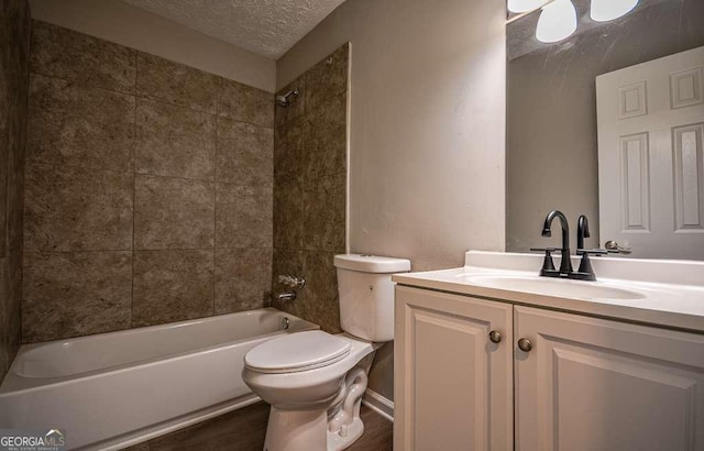 full bathroom with vanity, a textured ceiling, tiled shower / bath combo, and toilet