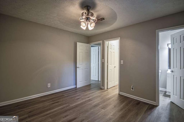 unfurnished bedroom featuring ceiling fan, dark hardwood / wood-style floors, and a textured ceiling