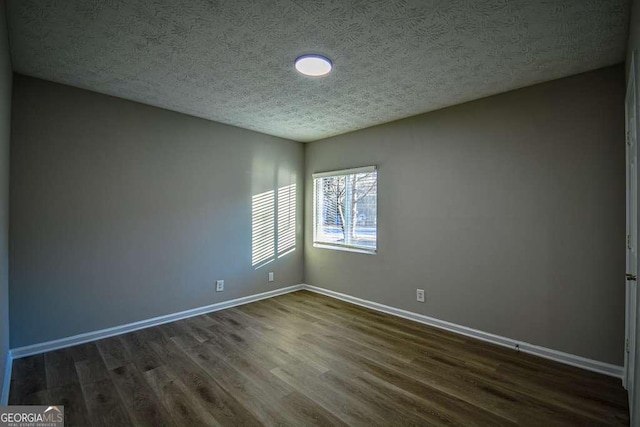 unfurnished room with a textured ceiling and dark hardwood / wood-style floors