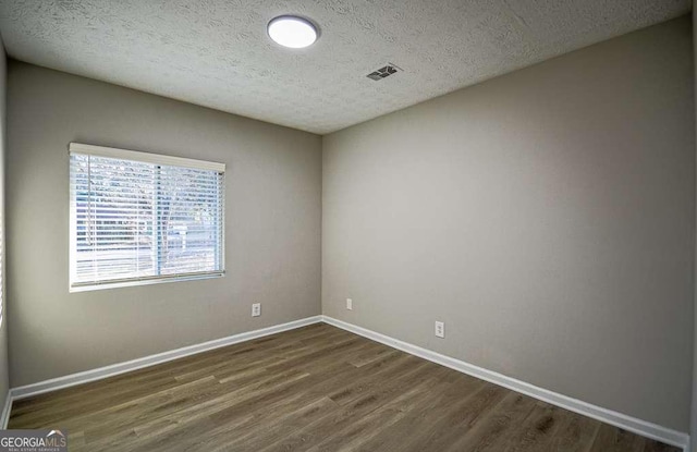 empty room featuring a textured ceiling and dark wood-type flooring