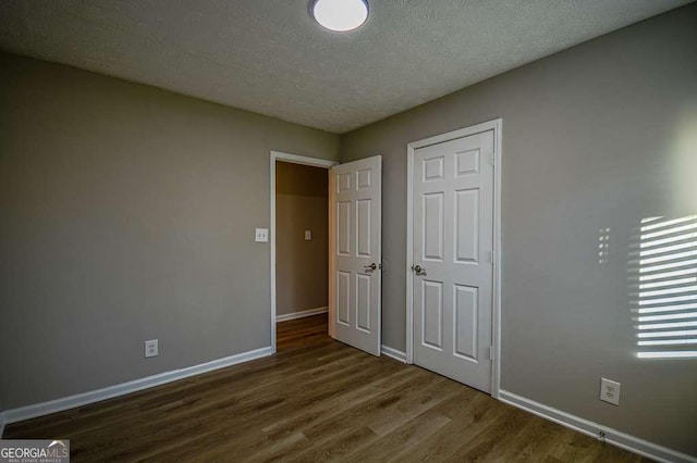 unfurnished bedroom featuring dark wood-type flooring and a textured ceiling