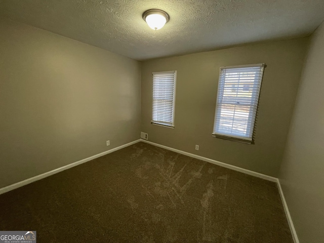 unfurnished room featuring dark colored carpet and a textured ceiling