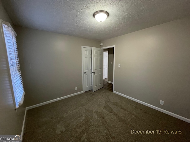 unfurnished bedroom featuring carpet floors, a textured ceiling, and a closet