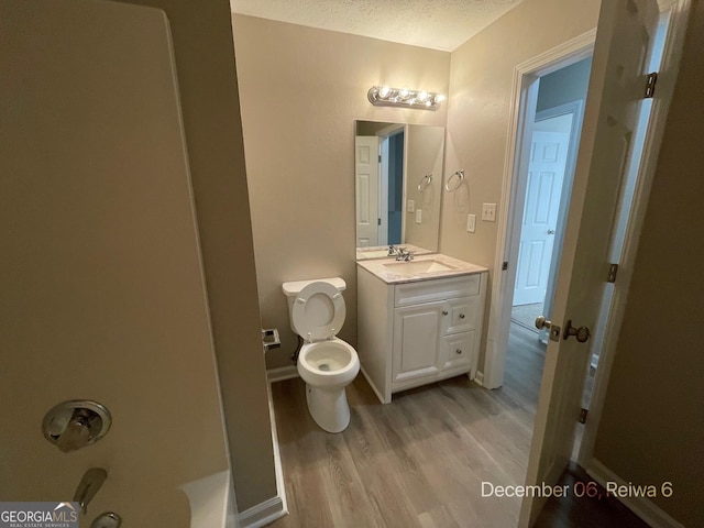 bathroom with toilet, vanity, a textured ceiling, and hardwood / wood-style flooring