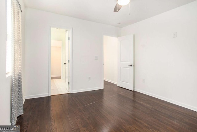 unfurnished bedroom with a closet, a walk in closet, dark hardwood / wood-style floors, and ceiling fan