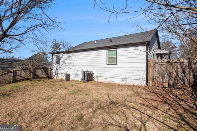 back of house with central air condition unit and a lawn