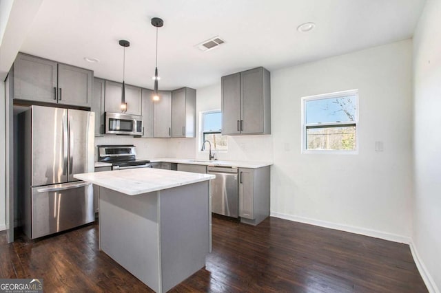 kitchen with pendant lighting, a center island, sink, gray cabinets, and stainless steel appliances