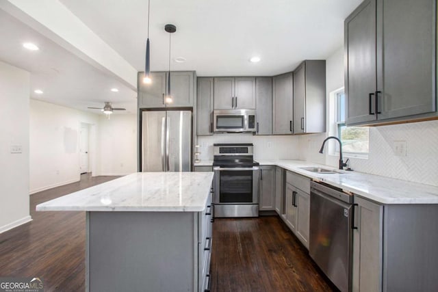 kitchen featuring ceiling fan, sink, hanging light fixtures, a kitchen island, and appliances with stainless steel finishes