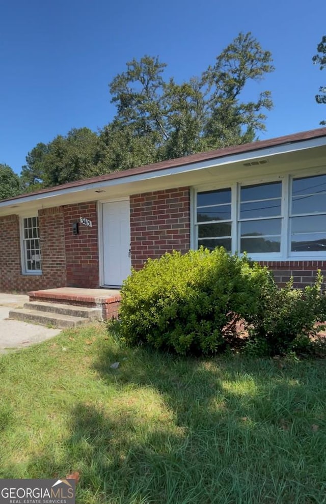 view of exterior entry with a yard