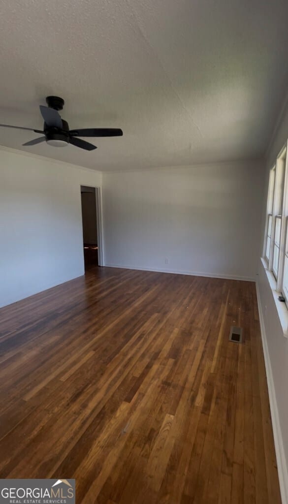 spare room with dark hardwood / wood-style floors, ceiling fan, and a textured ceiling