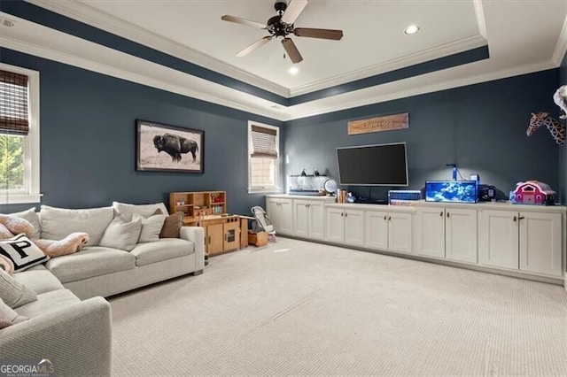 living room featuring a tray ceiling, plenty of natural light, light colored carpet, and ceiling fan