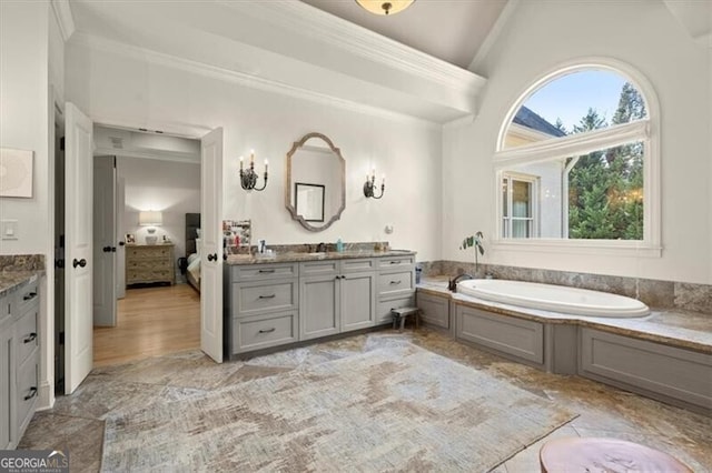 bathroom with ornamental molding, vanity, and a bathing tub