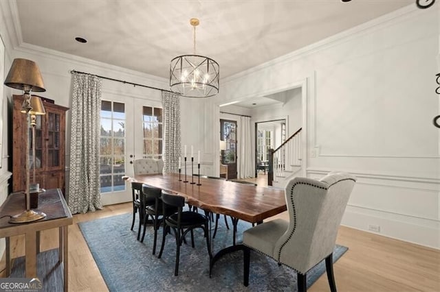 dining room featuring a chandelier, light hardwood / wood-style floors, crown molding, and french doors