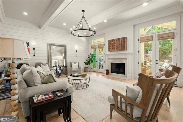 living room featuring french doors, a wealth of natural light, wooden walls, an inviting chandelier, and beamed ceiling