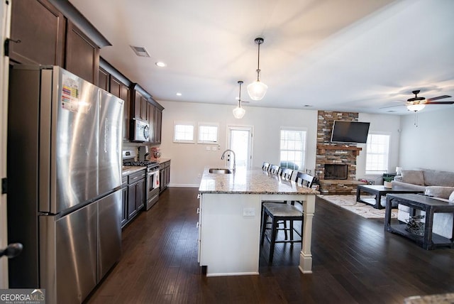 kitchen featuring dark brown cabinets, stainless steel appliances, sink, a breakfast bar area, and an island with sink