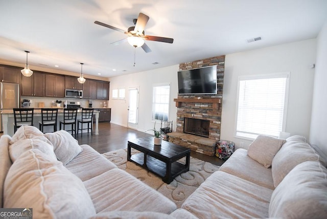 living room with a fireplace, ceiling fan, and dark hardwood / wood-style flooring