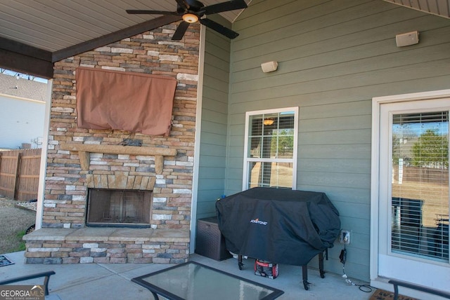 view of patio featuring an outdoor stone fireplace, area for grilling, and ceiling fan