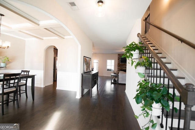 foyer entrance with dark hardwood / wood-style floors, beam ceiling, a fireplace, and coffered ceiling