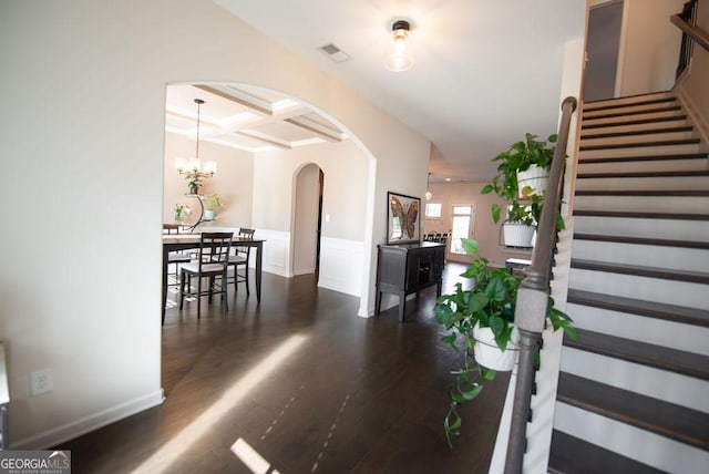 staircase with hardwood / wood-style flooring, a notable chandelier, beam ceiling, and coffered ceiling