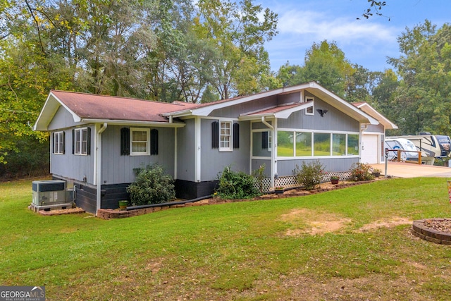 ranch-style house with a garage, a front yard, and central AC