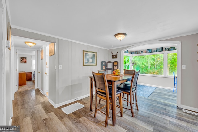 dining room with ornamental molding and light hardwood / wood-style flooring