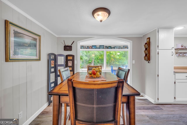 dining area with light wood-type flooring and ornamental molding