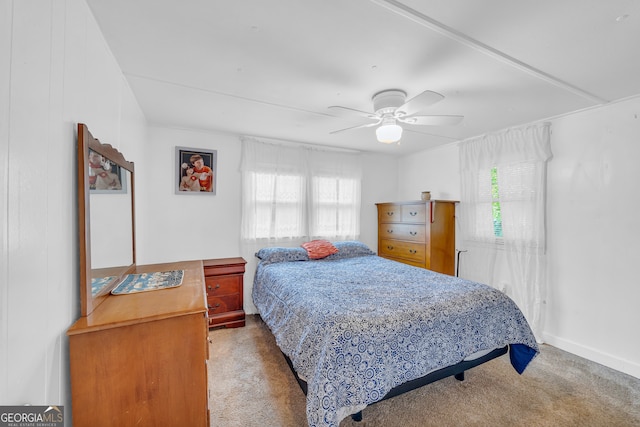 bedroom featuring ceiling fan, light carpet, and multiple windows