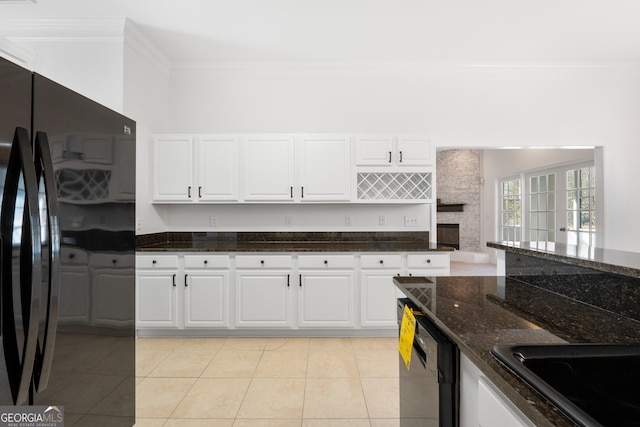 kitchen featuring black refrigerator, dark stone counters, light tile patterned floors, dishwasher, and white cabinets