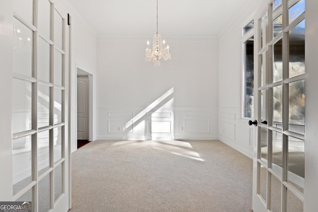 carpeted spare room featuring a chandelier and crown molding