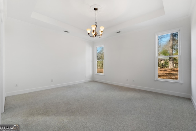 empty room featuring carpet, a chandelier, and a tray ceiling