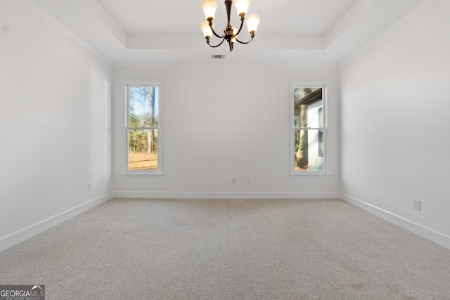 spare room featuring carpet flooring, a chandelier, and a tray ceiling