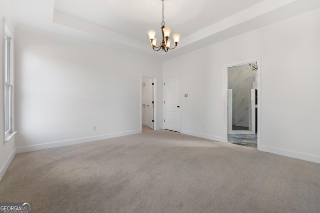 carpeted spare room featuring a raised ceiling and a notable chandelier