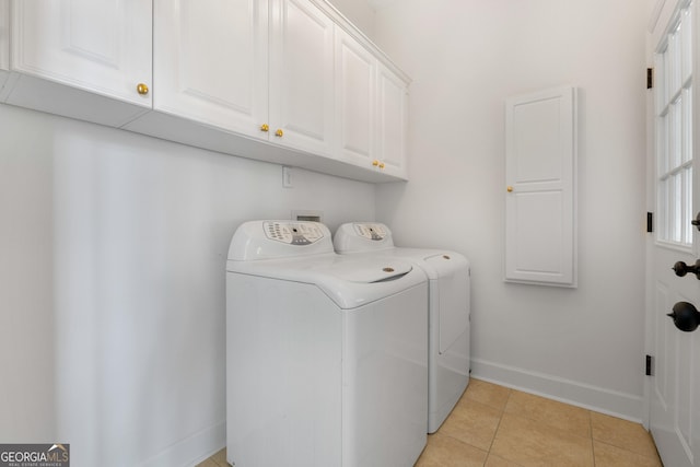 clothes washing area featuring separate washer and dryer, light tile patterned floors, and cabinets