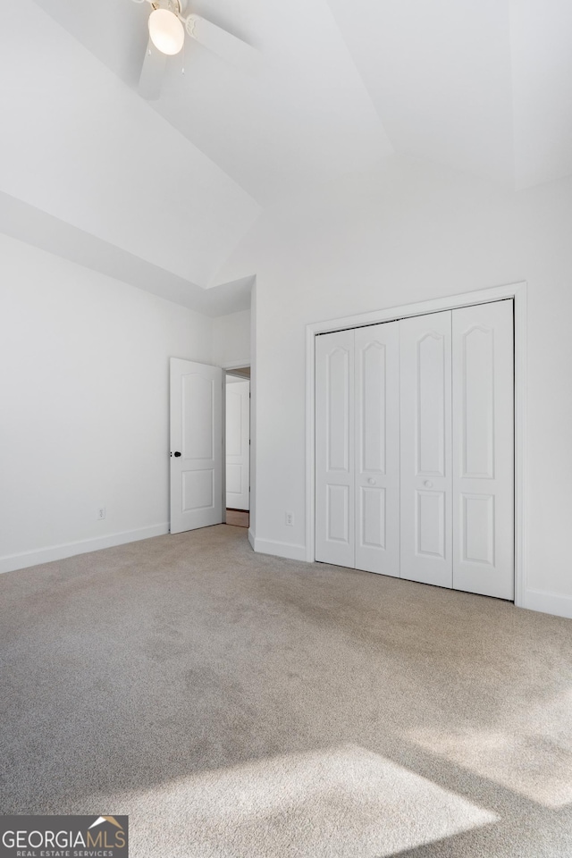 unfurnished bedroom featuring carpet flooring, ceiling fan, lofted ceiling, and a closet